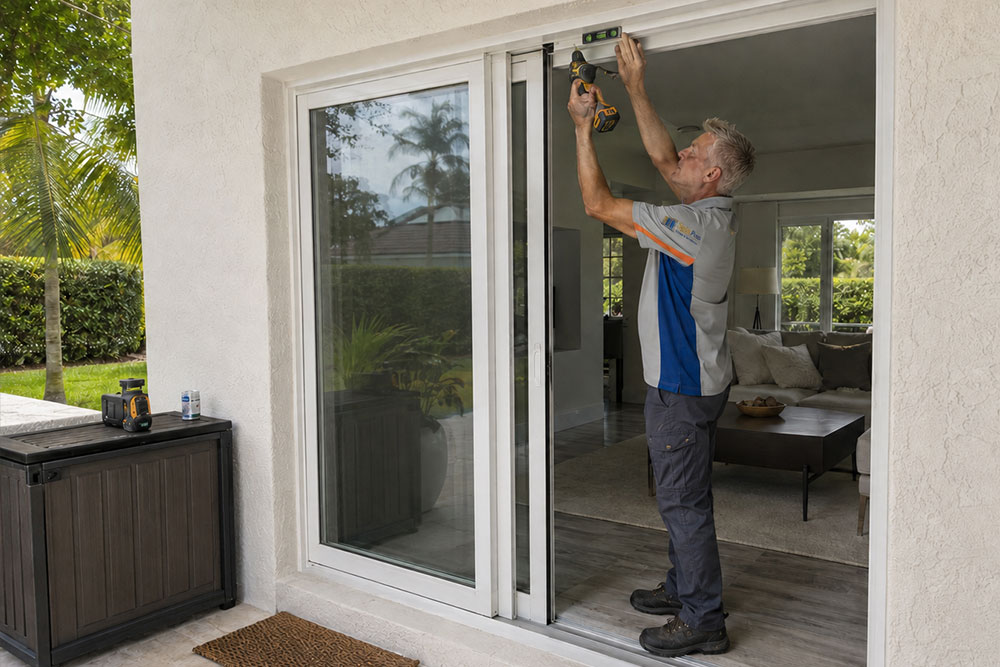 SpinPro technician adjusting a sliding glass door frame outdoors